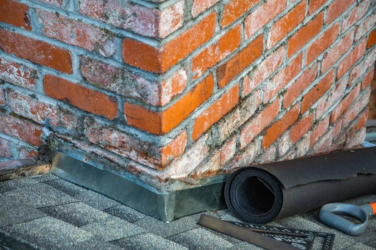 Worker troweling fresh mortar sealant onto a chimney crown